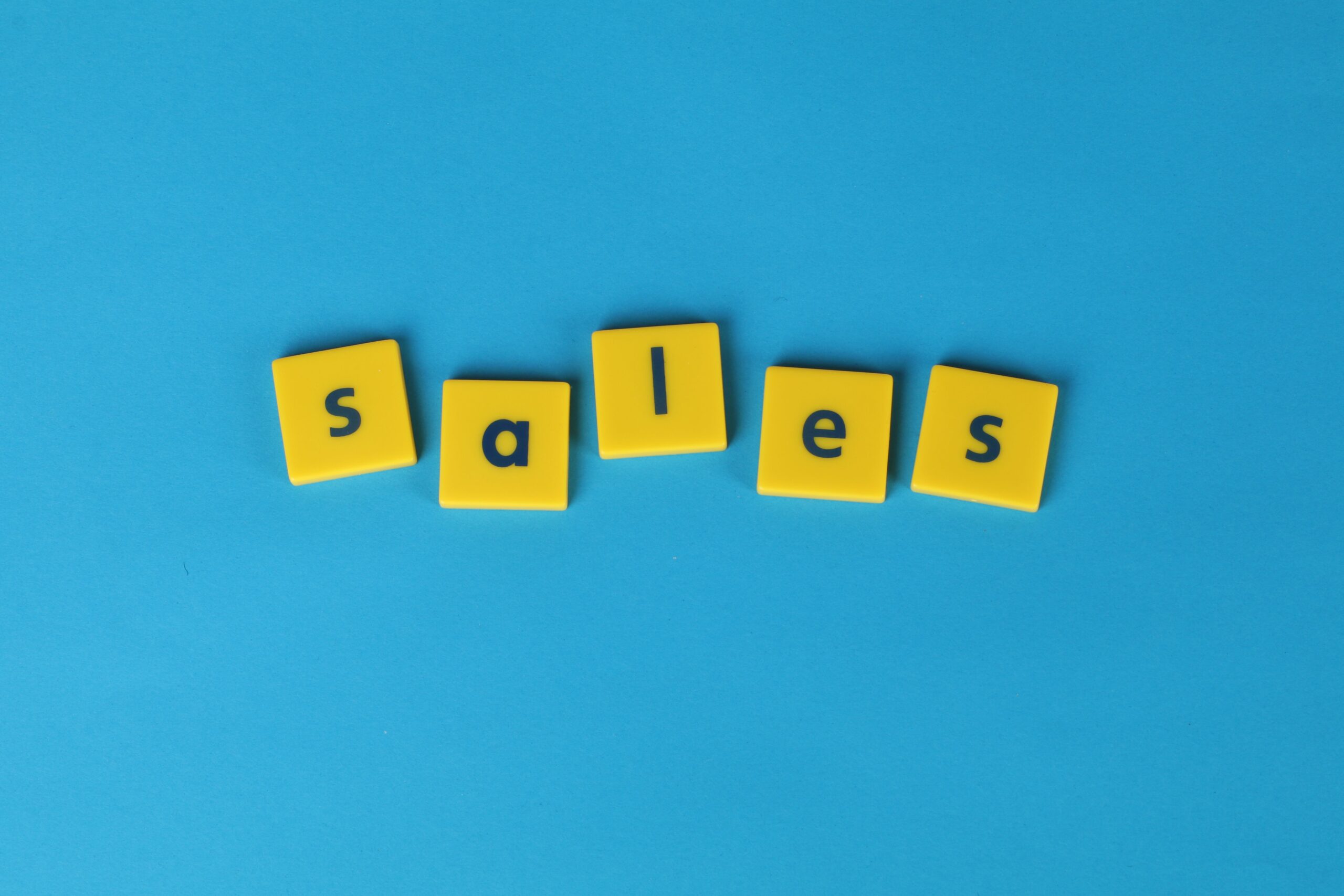 Yellow Scrabble tiles spelling 'sales' on a vibrant blue background. Perfect for marketing and business themes.